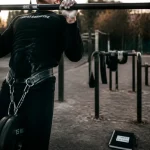 Street lifting : athlète en traction lestée sur barre fixe, dip belt et chalk